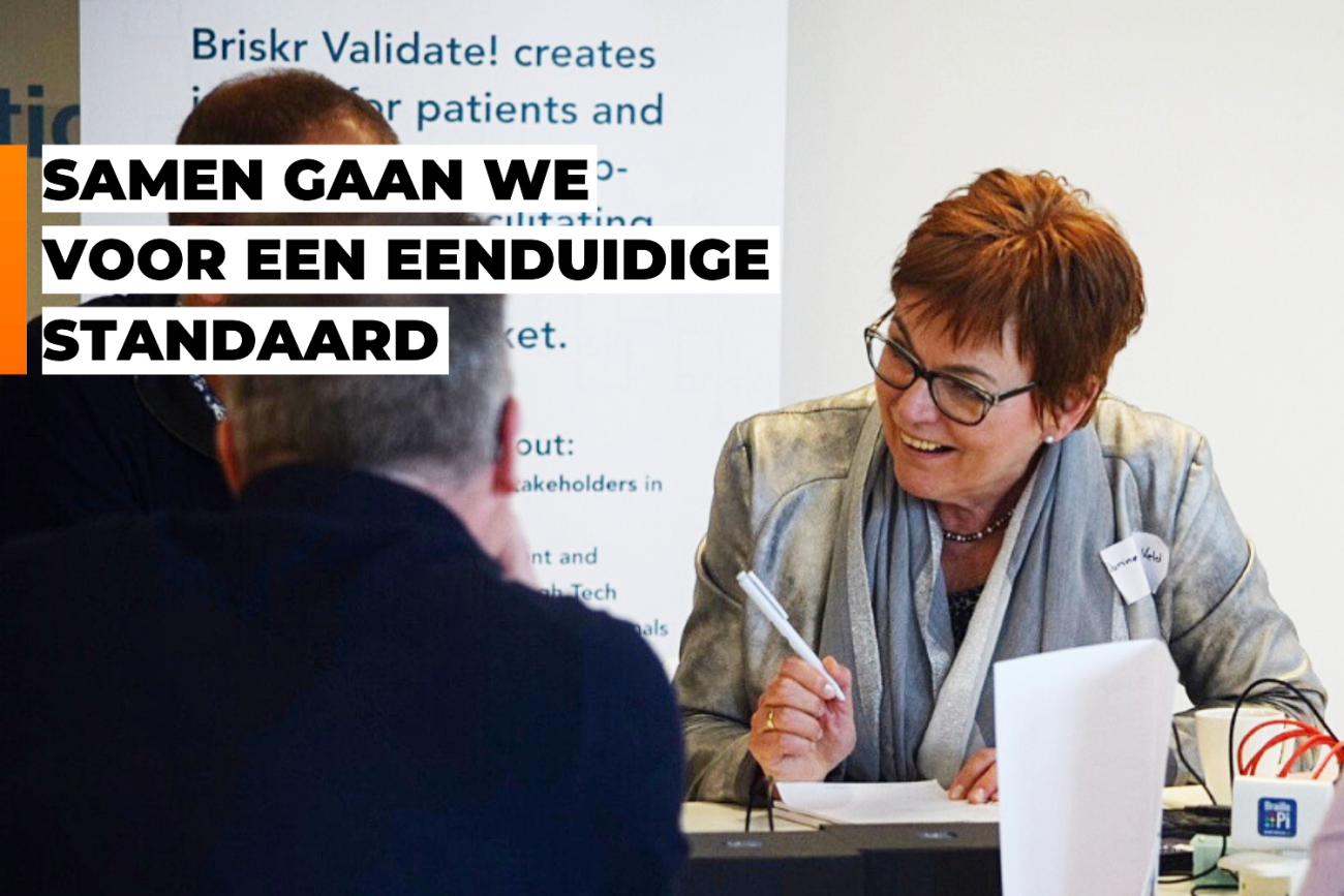 Dorine In 't Veld is in gesprek met anderen aan een tafel. Tekst: 'Samen gaan we voor een eenduidige standaard'