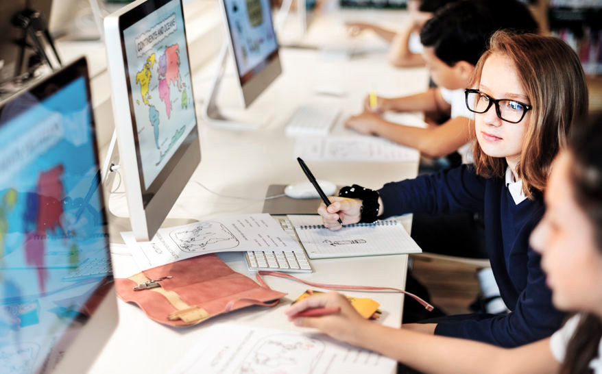 leerlingen naast elkaar aan een bureau kijken op beeldschermen met vergrotingen wereldkaart